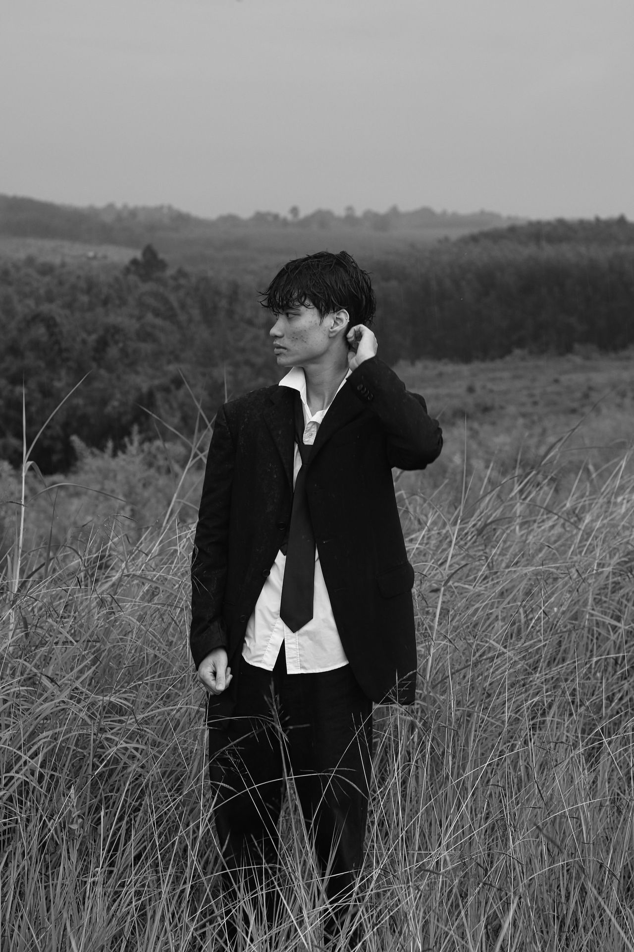 a man in a suit and tie standing in a field